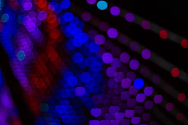 カラフルな青紫と赤のガーランドボケ焦点を当てない黒の背景に光の光線 — ストック写真