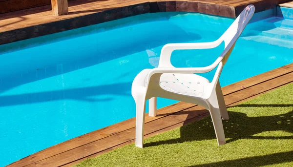 recreation and relaxation hotel yard space white chair furniture near swimming pool blue water