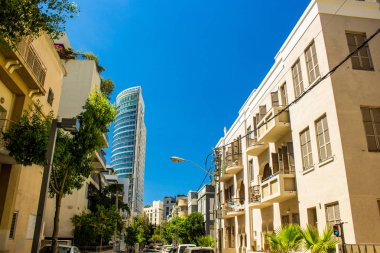 İsrail 'in Tel Aviv' in başkenti küçük beton evler dar sokak önü ve modern yüksek iş merkezi gökdeleni ve canlı mavi gökyüzü arka planı 