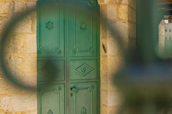 old city Jerusalem local urban ancient view Jewish door entrance to synagogue, unfocused metal fence frame foreground