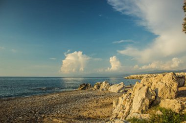 Dünya Cenneti 'nin sonu. Huzurlu manzaralı okyanus manzarası. Ufuk suyu arka planı ve yumuşak mavi gökyüzü ile kayalık kıyı şeridi. 