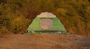 Bir tepe ve sonbahar renklerinde kamp çadırı. Kahverengi orman yeşilliği. Yaşam tarzı seyahat konsepti.  