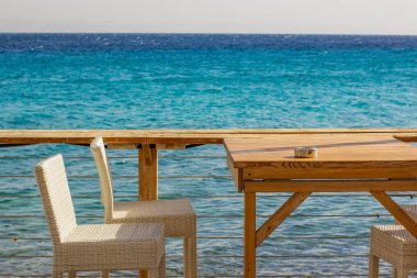 Bahçe kafesi ahşap masa ve deniz kıyısı bölgesi arka planında yemek yemek için rahat bir alan, metin veya yazıtlarınız için boş kopya alanı 