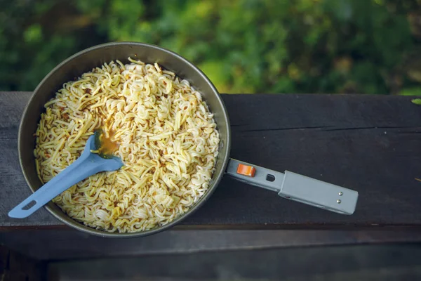 outdoor camp food pasta in small pan travel life style concept top view photography wooden and unfocused natural background copy space for your text