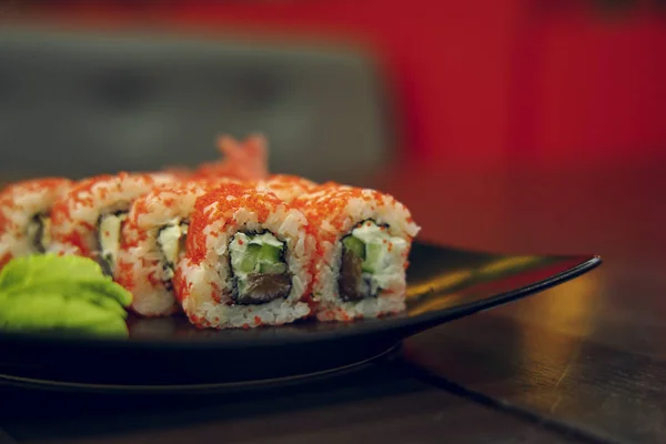 Japanese cuisine food photography sushi rolls on black plate cafe table unfocused twilight background environment empty copy space for your text