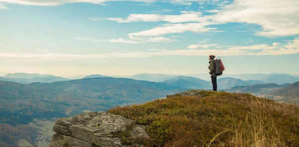 Seyahat tarzı sırt çantalı bir adam kalır ve güzel, huzurlu dağlık arazi manzarasının tadını çıkarır. Ekim ayının sonbahar sezonu manzarası.