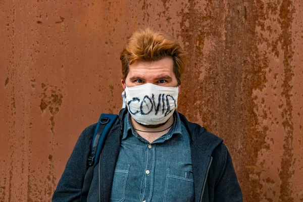 adult man in hand made face mask for respiration and health care social distance portrait on rusty wall background space