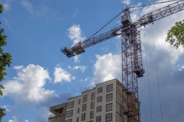 Vinç inşaatı endüstriyel şehir görüntüsünü aşağıdan mavi bulutlu gökyüzü arka planıyla birlikte işlemektedir