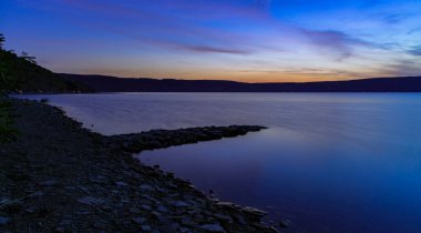 Huzurlu bir akşam manzarası vahşi nehir kıyısı. Alacakaranlıkta insanlar olmadan. Gün batımından sonra karanlığın aydınlanması.