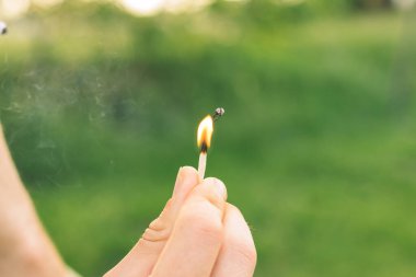 Ahşap ateş alevi insan elinde makro fotoğrafçılık odaklanmamış arkaplanda yeşil renk alanı burada metin için bulanıklaştırılmış