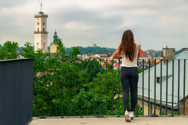 travel destination sightseeing wallpaper poster concept of attractive girl back to camera enjoy by European old city from top view point in Ukraine Lviv