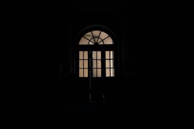 Eski evdeki kadim kemer şekilli kapı. İçerideki uzay siyah arka plan. Kapalı mekan mimarisi.