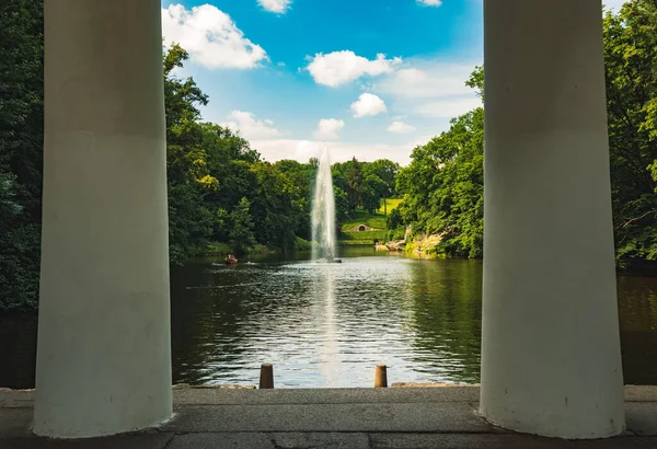 Park manzarası yaz günü göl çeşmesinin manzarası. Balkon ön planda mermer sütunlar.