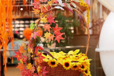Sentetik çiçekleri sepete asan iç tasarım elementi. Güneş ışığıyla yakın görüş. Sonbahar estetik sıcak renkler.