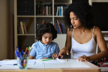 Anne, oğluna evde ders veriyor.