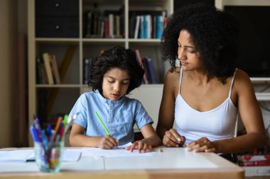 Anne, oğluna evde ders veriyor.