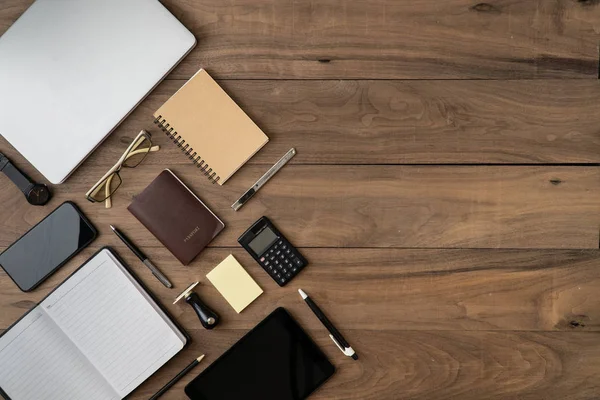 Accesorios de negocios lista de objetos copyspace plano poner en la mesa de madera con ordenador portátil Teléfono móvil Cuaderno Tablet Pasaporte Calculadora Lista de recordatorios Lápiz y anteojos . — Foto de Stock