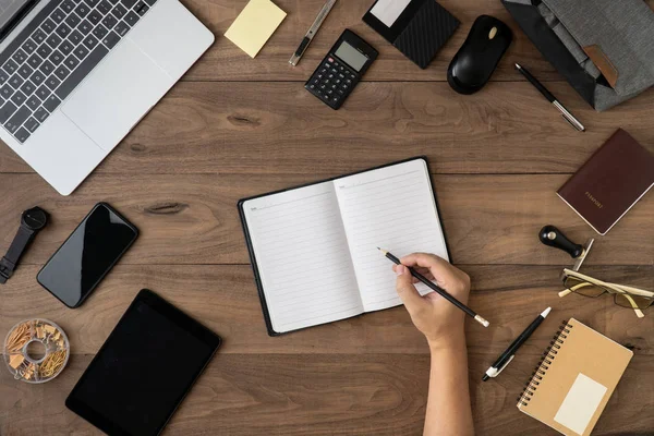 Rechte Hand hält Bleistift auf leere Notizbuch-Liste mit Bürozubehör auf Tisch flach lay.working on office desk flach lay.to Liste und Besprechung Erinnerungsliste auf Notebook-Konzept. — Stockfoto