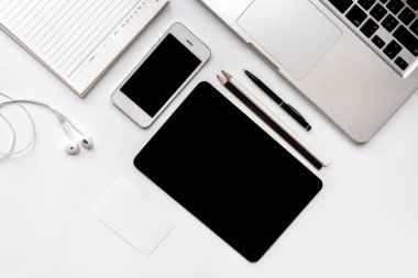 Ofis aksesuarları Top View.Laptop bilgisayar akıllı telefon kalemleri ve kulaklıklar beyaz arka planda izole edilmemiş.Serbest çalışma kavramı için çalışan aygıtlar.