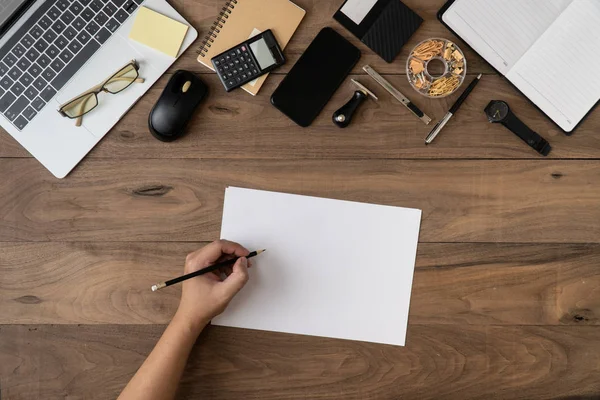 Mão esquerda escrevendo informações de mensagem em modelo de lista de notebook vazio com acessórios de escritório na mesa plana lay.Working mesa de escritório flat lay.To fazer lista no conceito de documento . — Fotografia de Stock