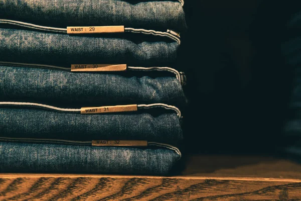 Stacked jeans with multiple waist sizes on shelves or closets.