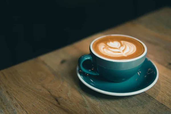 Secangkir kopi dengan latte art disajikan di atas meja kayu . — Stok Foto