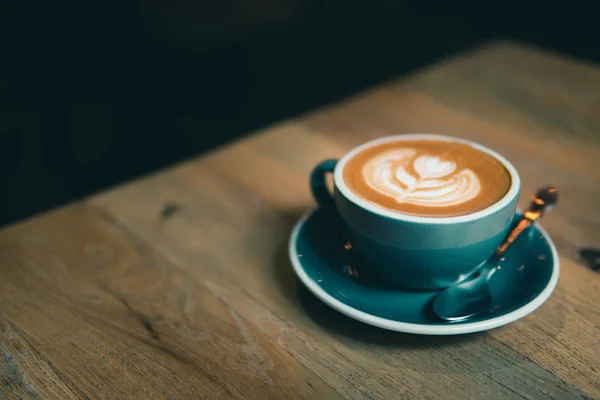 Secangkir kopi dengan latte art disajikan di atas meja kayu . — Stok Foto