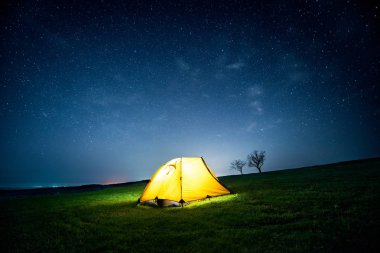 Yıldızlı gökyüzü altında gece dağda kamp çadır parlayan