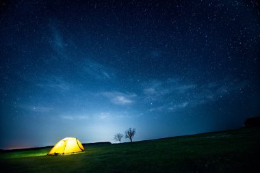 Yıldızlı gökyüzü altında gece dağda kamp çadır parlayan