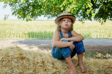 Çok güzel çocuk saman üzerinde oturur