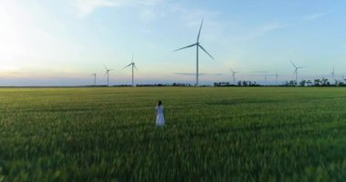 Güzel kız yel elektrik enerjisi üretimi için bir yeşil buğday sahada ayakta