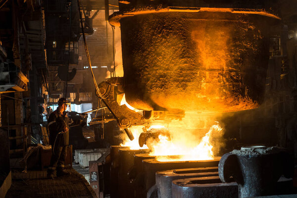 Zaporozhye/ Ukraine - 07.27.2015: two steelworkers at work near the tanks with hot metal. Zaporizhstal JSC