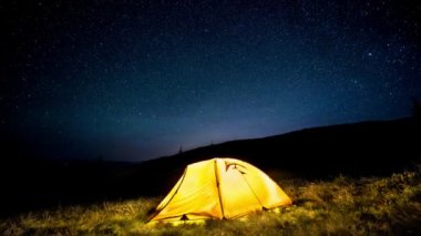 Hızlandırılmış. Yıldızlı gökyüzü altında gece dağ ormanda kamp çadır parlayan 