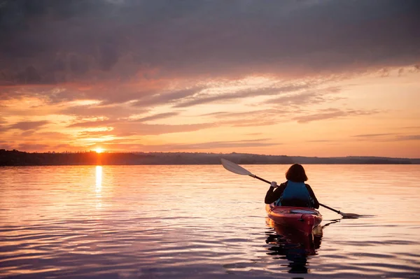 在风景秀丽的日落河上的独木舟的妇女 — 图库照片