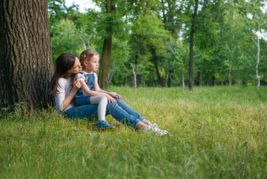 Anne ve kızı bir ağacın yanında oturuyor
