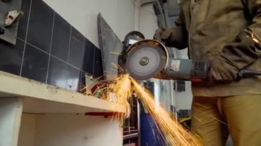 Öğütücü kullanan işçilere yakın çekim bir atölyede metal kesiyor.
