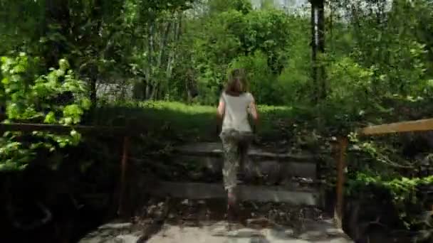 陽気な十代の女の子は春の森の芝生に沿って実行されます — ストック動画