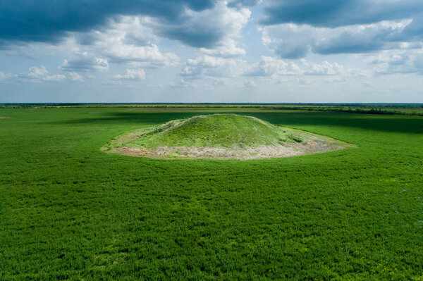 Scenic view of the burial mound of the Scythian king in a green field. Aerial view.