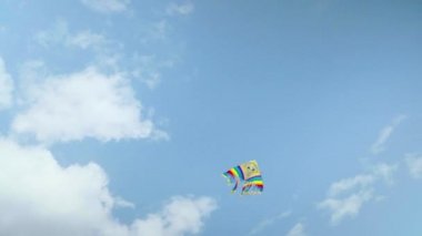 Bulutlar ile mavi gökyüzüne karşı uçan renkli uçurtma