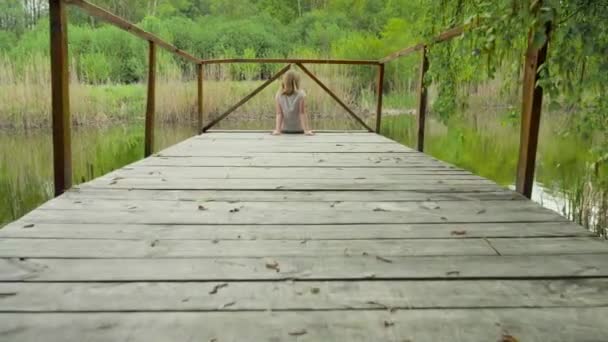 Teenager Mädchen Sitzt Auf Einer Holzbrücke Der Nähe Des Flusses — Stockvideo