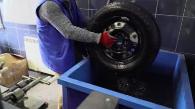 İşçi lastik servisinde tekerlek yıkar.