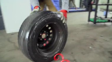 İşçi bir araba tamirhanesinde tekerlek çeviriyor.