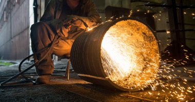 İşçi bir atölyede endüstriyel kaynak yapıyor.