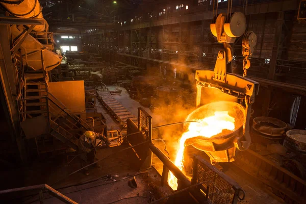 Çelik işçisi tankların yanında sıcak metalle çalışıyor.