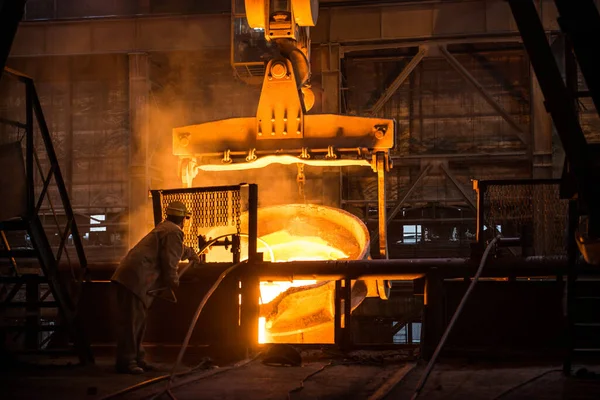 Çelik işçisi tankların yanında sıcak metalle çalışıyor.