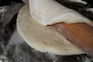 Siyah arka planda merdaneli pizza hamuru.