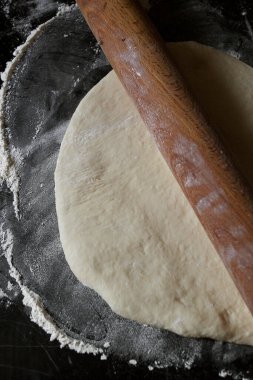 Siyah arka planda merdaneli pizza hamuru.