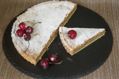 badem kremalı tart (frangipani) pudra şekeri ve kirazla süslenmiş.