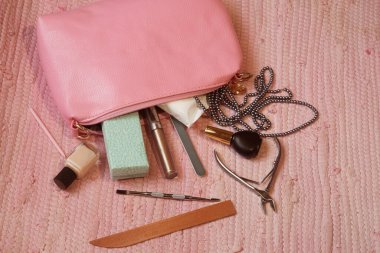 Pembe bir halıda el ve ayak bakımı için pembe bir makyaj çantası.