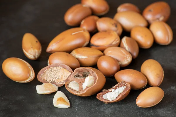 the kernel of the argan nut is broken on a black background with whole nuts, close-up
